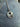 Silver necklace with a round pendant on a gray stone surface